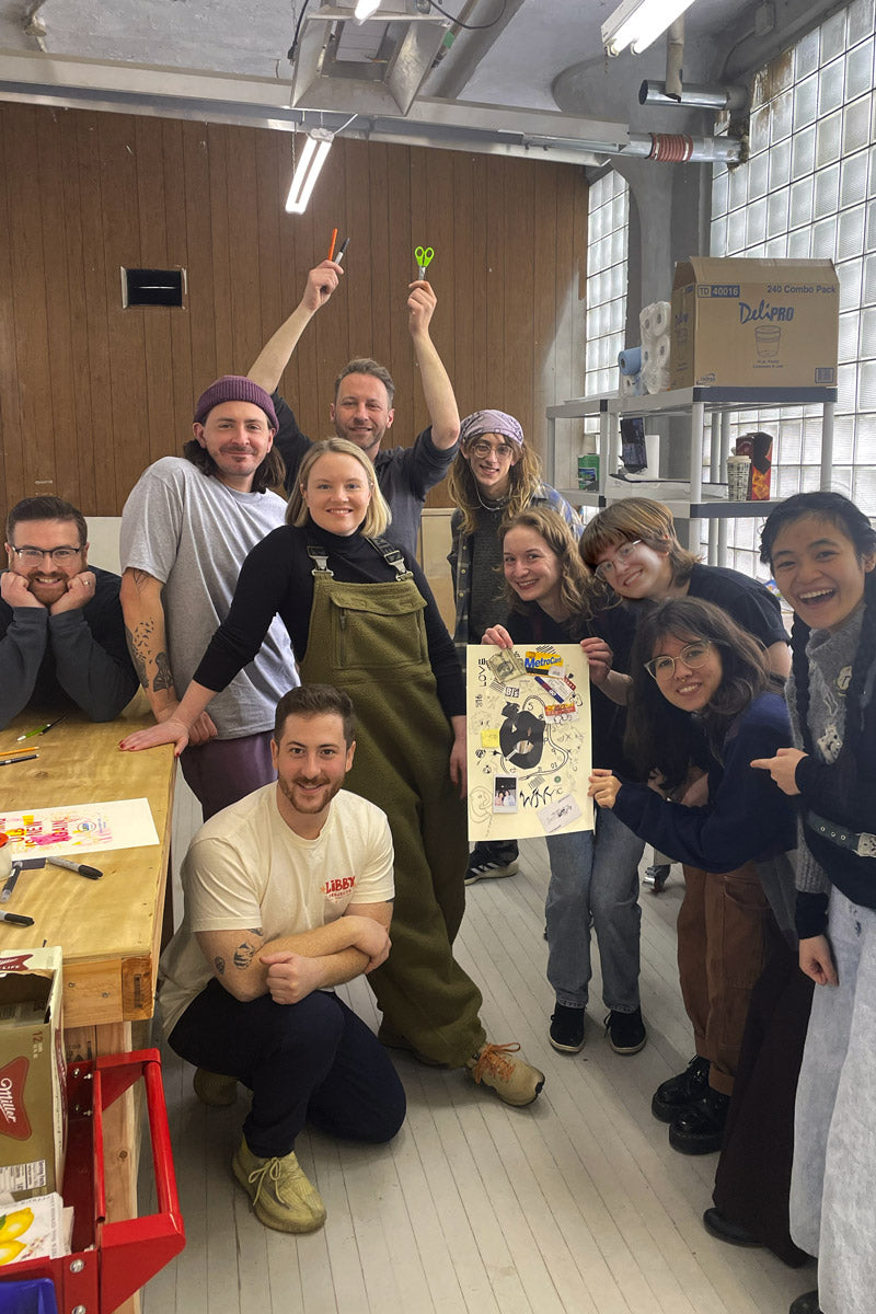 A group of smiling workshop goers show off the risograph poster they created.